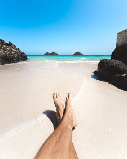 A vertical shot of a person's feet in the sand at a beach