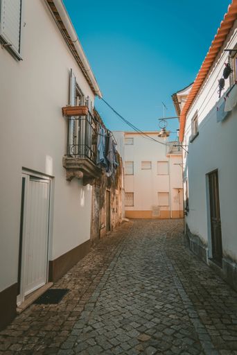 A vertical shot of a pathway in the middle of white buildings under a blue sky