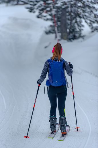 A back view of skiing woman with a black backpack