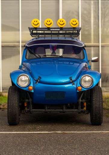 A vertical shot of a Blue Volkswagen Beetle with smiley lamps converted to a Beach Buggy