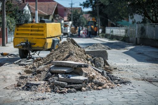 A demolished parts of asphalt road and dirt piled on the center of the road
