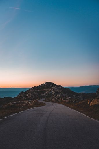 A narrow road leading to a rocky cave under the beautiful sunset sky