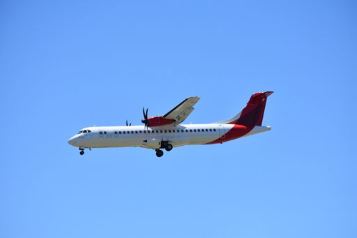 A closeup of a commercial airplane flying high against a clear blue sky
