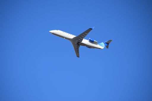 A photo of United Airlines in flight against a bright blue sky on a sunny day