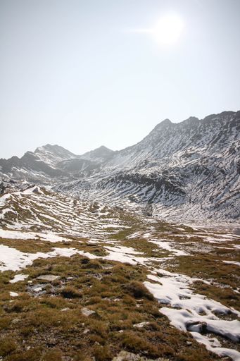 A vertical shot of high rocks covered in snow on a sunny day with a blue sky in the background