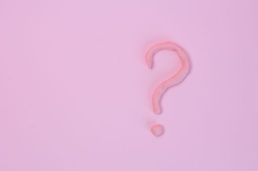 A question mark from modeling clay isolated on a pink background