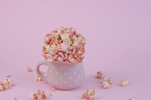 A closeup shot of a cupof popcorn isolated on a pink background