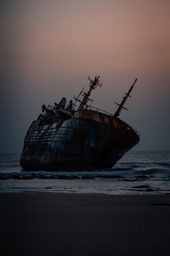 A vertical shot of a historic dirty old ship after a shipwreck on a seashore