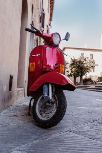 A vibrant red Vespa scooter parked on the street in Madrid.