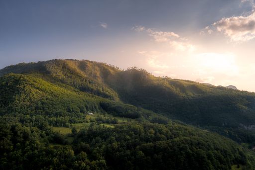 A beautiful view of hills with green trees under the blue sky during sunrise