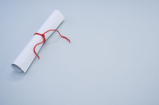 A closeup shot of a white paper scroll tied with red thread isolated on a gray background