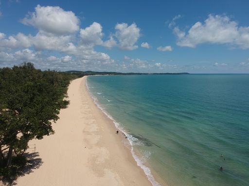 An aerial shot of the sandy Desaru beach in Malaysia alongside the clam blue sea on a sunny day