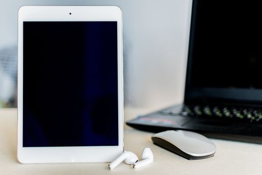 A tablet with black screen next to a laptop on a desk - technology and business concept
