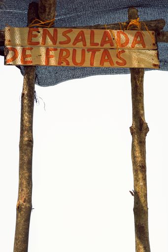 A vertical shot of a wooden board beach sign with Spanish writing ''Ensalada De Frutas - Fruit Salad''