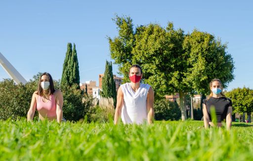 A closeup shot of friends in facial masks doing yoga in the park - new normal concept