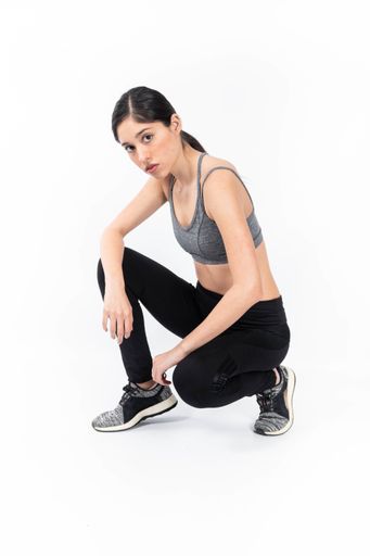 A vertical shot of a Hispanic female posing while wearing sportswear with a white background