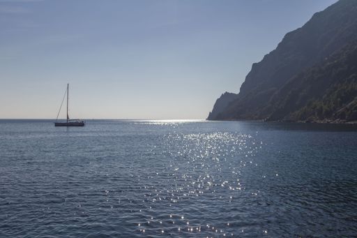 An aerial view of boat floating in sea surrounded by mountains
