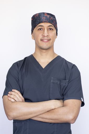 A vertical portrait of a Hispanic dentist with crossed hands