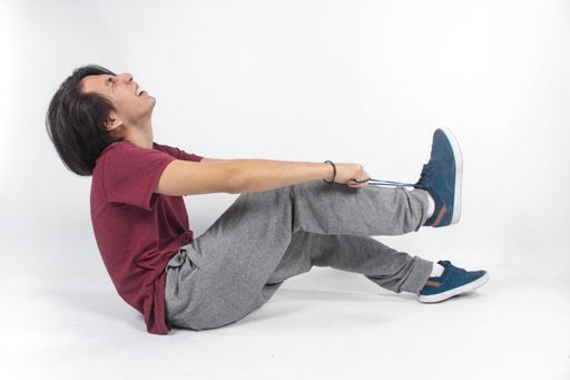 A shot of a man sitting and tying sneakers with a happy face