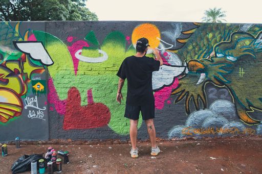 An artist creating graffiti on a wall in different colors