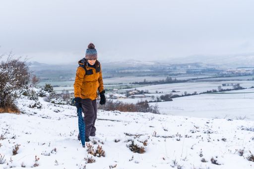 A woman in a yellow jacket at a snowy park during winter in the town of Opakua near Vitoria in Araba, Basque Country, Spain