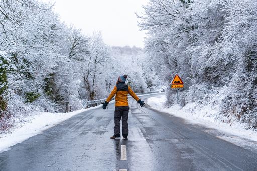 A woman in a yellow jacket on an icy road lined with bare trees during winter in the town of Opakua near Vitoria in Araba, Basque Country, Spain