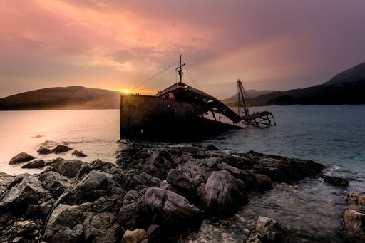 The silhouette of an old half-drowned ship at the coast of a sea at sunset