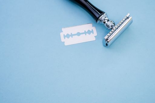 A top view of mechanical razor and blade isolated on blue background