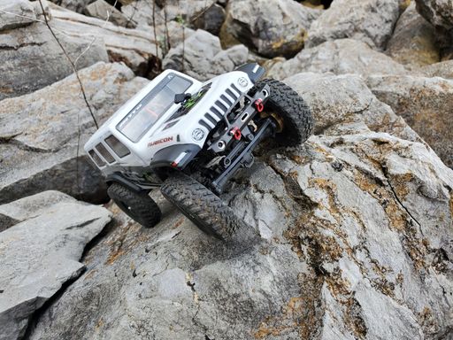 A toy car Jeep Wrangler on stones by the lake with a view of nuclear power plant