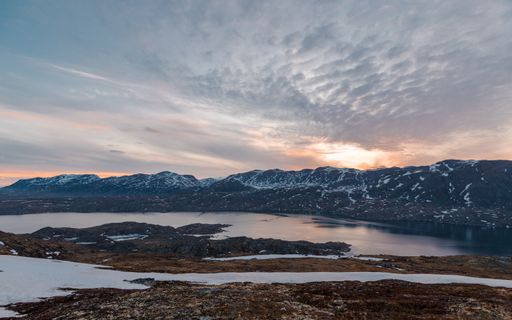 A mesmerizing shot of beautiful mountains and a lake covered with snow and iceduring the sunset