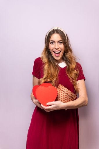 A vertical shot of a white Caucasian woman holding gift boxes and happily posing