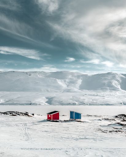A vertical shot of a snow-covered mountainous area with two small buildings