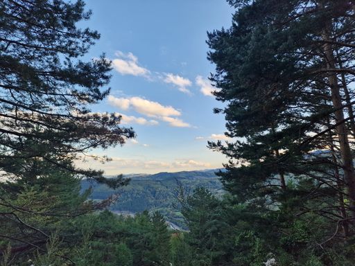 A beautiful view of green forested hills against the blue sky with some clouds in spring