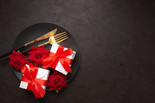 A closeup of roses, gifts, knife, and fork on a plate