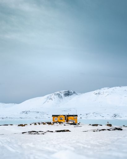 A vertical shot of a snow-covered mountainous area with a cute yellow building
