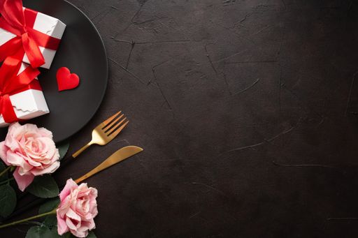 A closeup of roses, knife, fork, and gifts on a plate