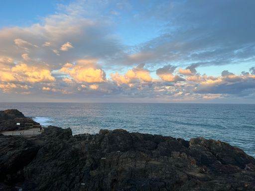 An aerial view of sea with rocky beach during sunset