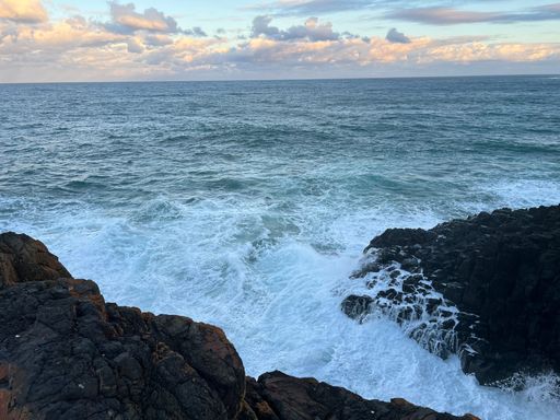 A closeup shot of cliffs and turbulent sea washing the coastline during sunset