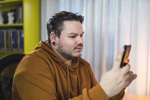 A selective focus shot of a moody cool guy with piercings sitting in a room using his phone