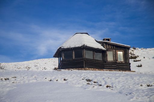 A cozy log cabin on a snowy hill during winter
