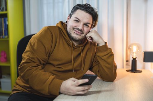 A selective focus shot of a cool cheerfulguy with piercings using his smartphone in a room