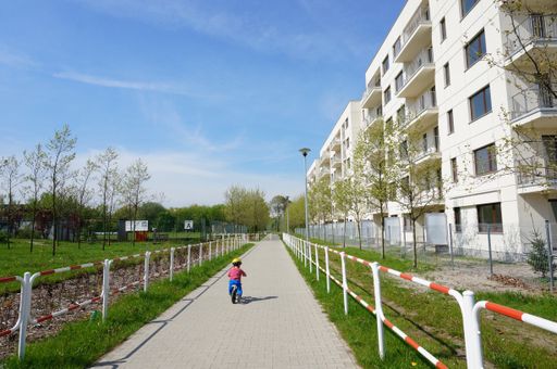 Footpath with child on bike next to a modern apartment