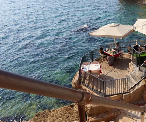 A high-angle shot of a couple sitting on the veranda of a restaurant above the sea in Acre, Israel