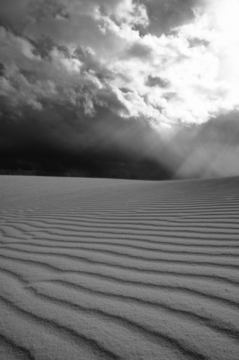 A black-and-white vertical shot of a wide desert in cloudy sky background
