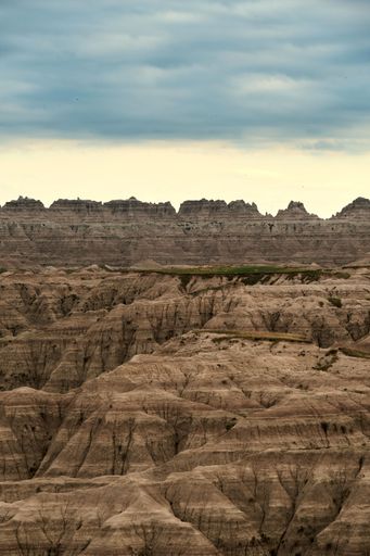 A vertical aerial view of huge rock formations in a canyon park in cloudy sky background