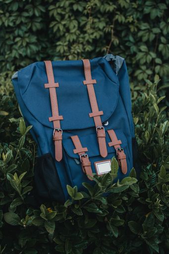 A selective focus shot of a blue backpack in the garden