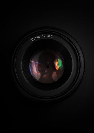 A camera lens reflects the viewer