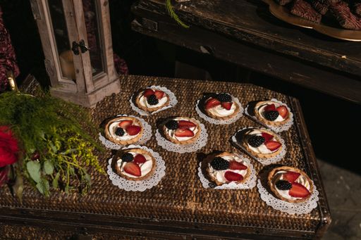 A shot of flowers and delicious small cakes with fruits on a wooden table