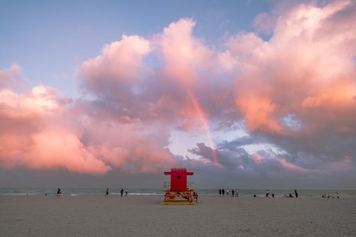 The Miami Beach under the bright cloudy sky with  a rainbow in the center