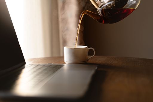 A view of pouring tea from tea pot near laptop